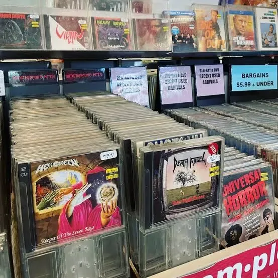 A record-store bin of heavy metal CDs, with Helloween, Death Angel and a horror compilation in the front row under divider cards for underground metal